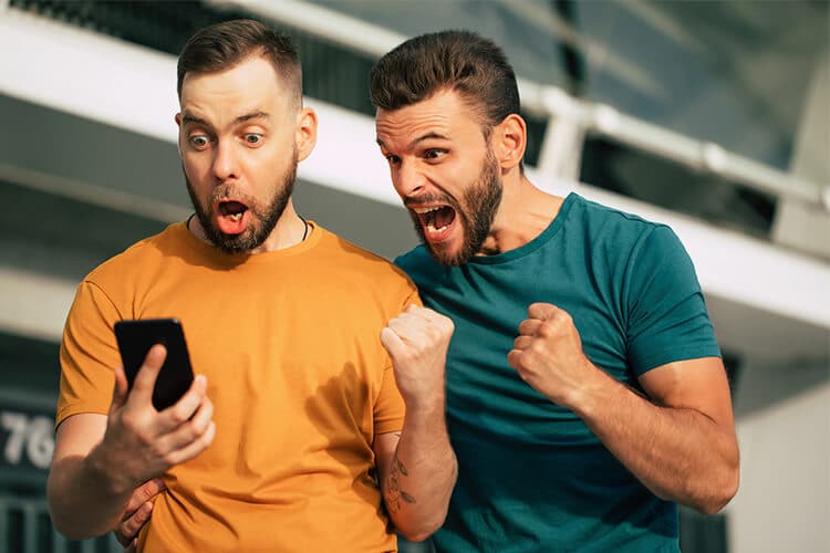 dos-hombres-con-un-celular-festejando-que-han-ganando-dinero-smartphone-teléfono-movil-buso-amarillo-buso-verde