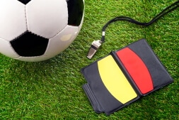 pelota-de-fútbol-sobre-el-pasto-con-un-silbato-de-árbitro-y-las-tarjetas-amarillas-y-rojas
